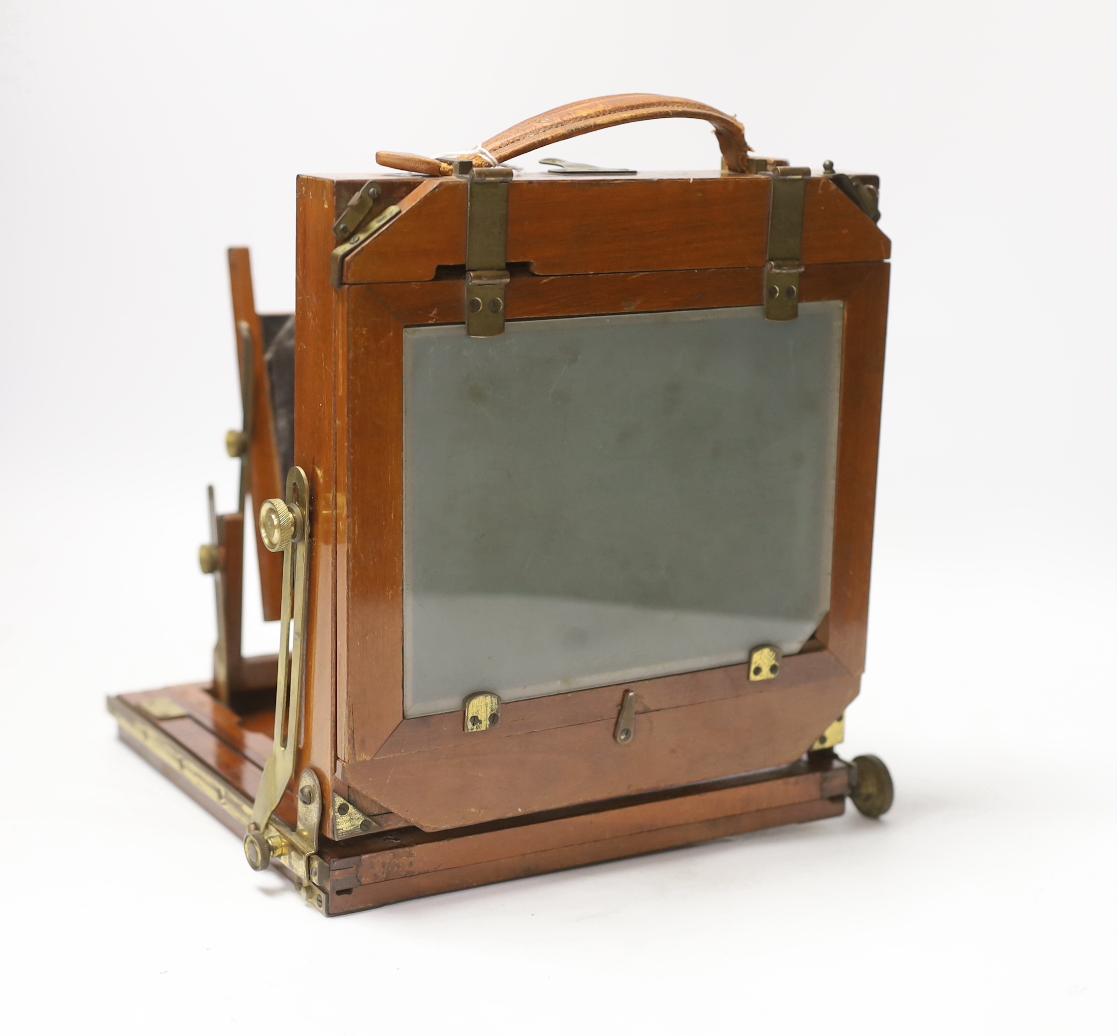 A late nineteenth century brass and mahogany half plate bellows camera with a lens and a shutter action by Taylor, Taylor & Hobson, Leicester, together with a negative holder